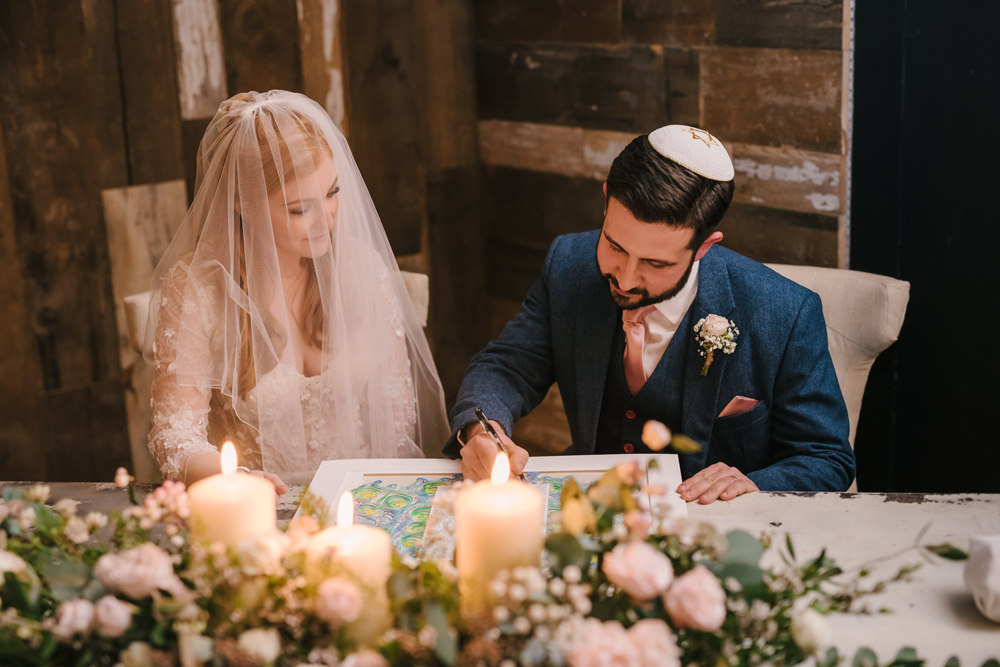 A modern couple signing their Ketubah at their wedding